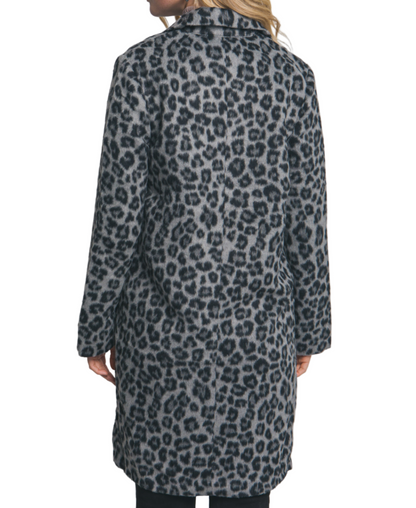 Person wearing a leopard print coat against a plain background