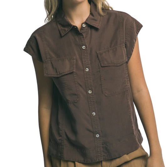 Woman wearing a brown sleeveless shirt against a gray background