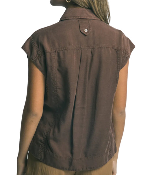 Woman wearing a brown sleeveless shirt against a plain background