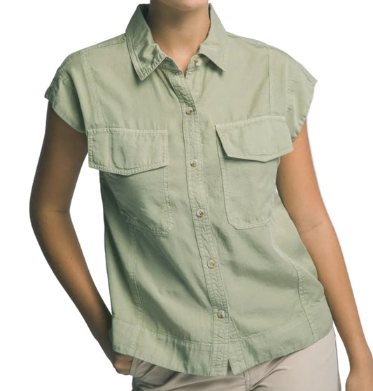 Woman wearing a light green sleeveless shirt with pockets on a plain background