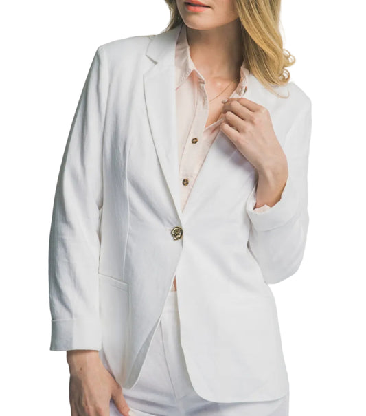 Woman wearing a white blazer over a light pink shirt on a plain background