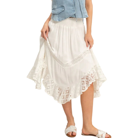 Woman wearing a denim top and white lace skirt on a plain background