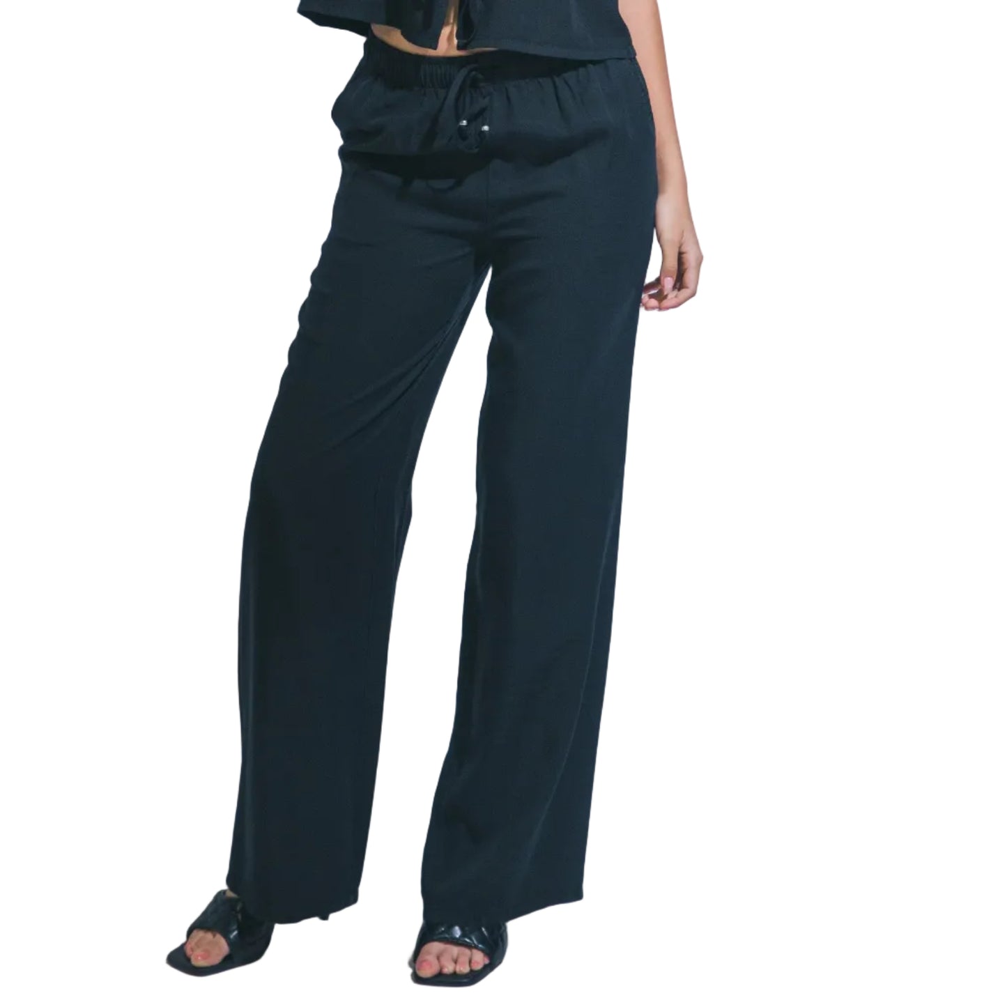 Woman wearing a black sleeveless top and pants against a white background