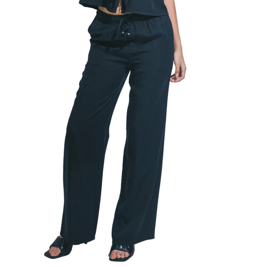 Woman wearing a black sleeveless top and pants against a white background