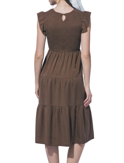 Woman wearing a brown dress against a light gray background
