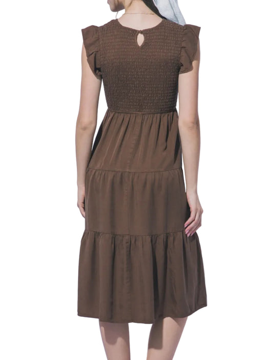 Woman wearing a brown dress against a light gray background