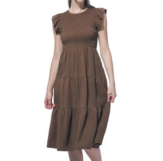 Woman wearing a brown dress against a light gray background