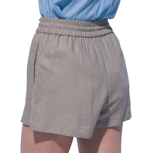Person wearing beige shorts with a light blue top against a plain background