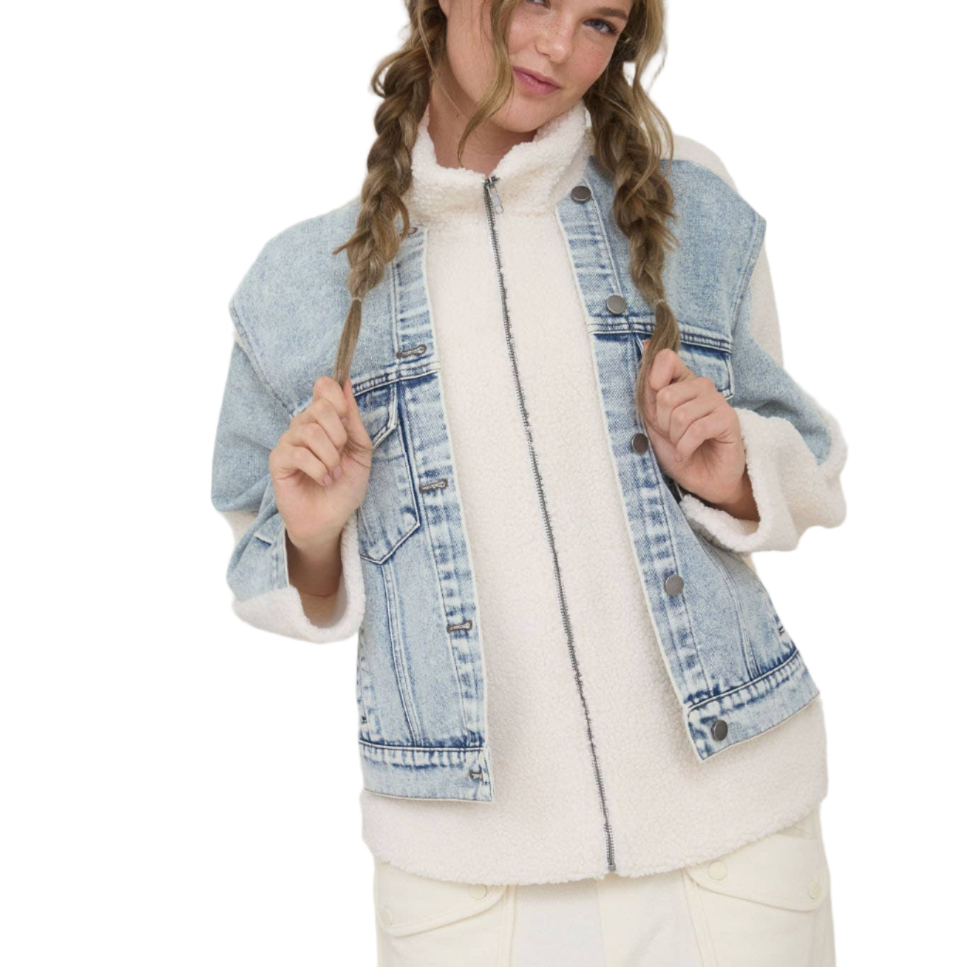 Woman wearing a denim vest over a white outfit against a plain background