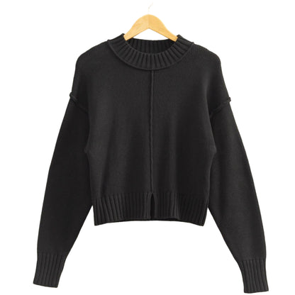 Black sweater on a wooden hanger against a beige background