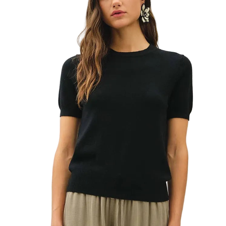 Woman wearing a black top and beige pants on a white background