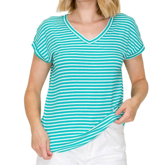 Woman wearing a turquoise and white striped shirt with white shorts on a beige background