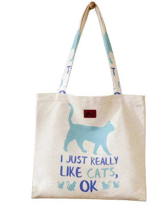 Tote bag with a blue cat illustration and text on a wooden surface.