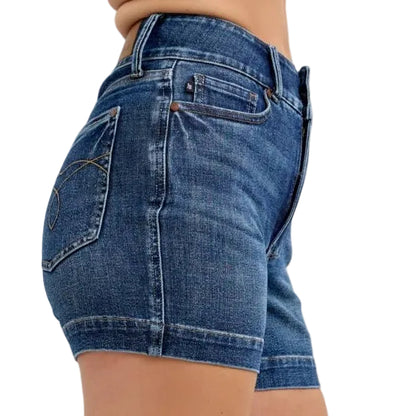 Denim shorts worn by a person on a plain background