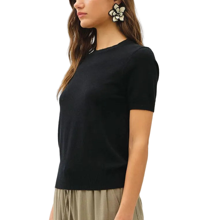 Woman wearing a black top and beige wide-leg pants on a white background