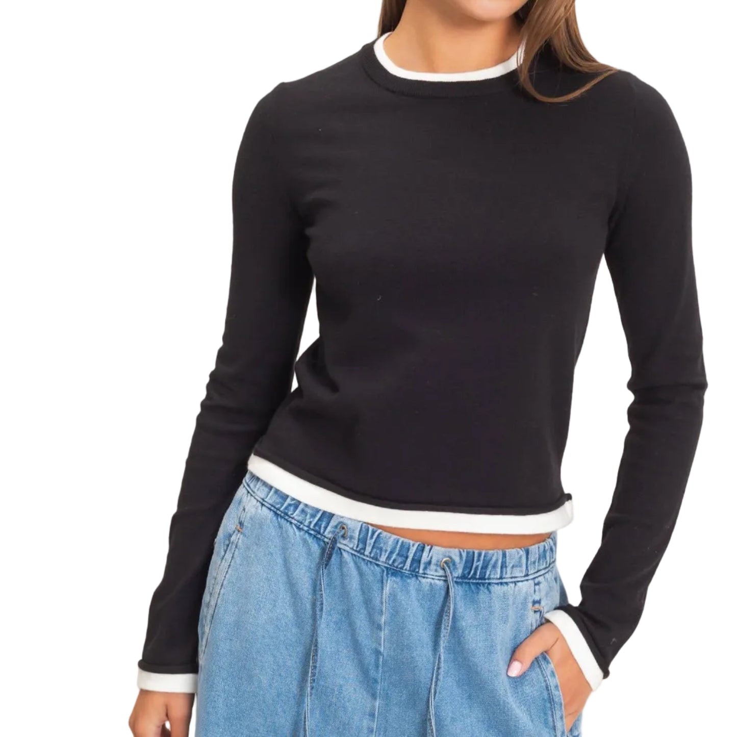A woman modeling a black long-sleeve crewneck sweater with white ribbed trim at the collar, cuffs, and hem, paired with light blue jeans against a plain light beige background.