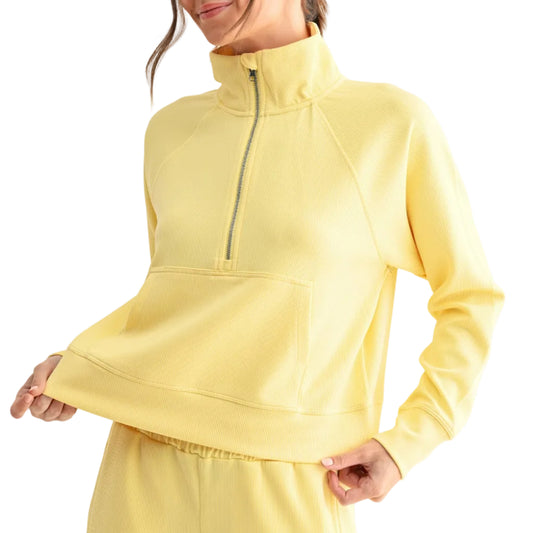 Woman wearing a yellow outfit with a quarter-zip top and pants on a white background