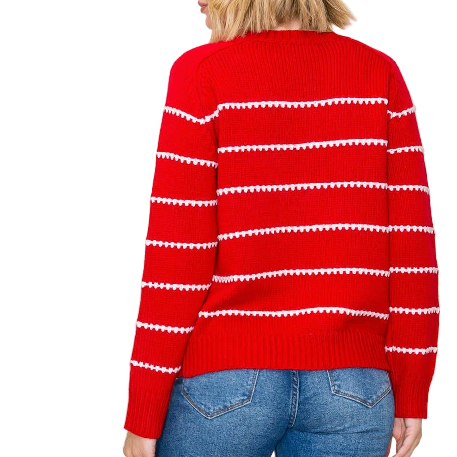 Person wearing a red sweater with white stripes and blue jeans on a beige background