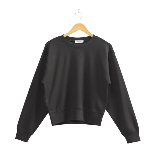 Black sweatshirt on a wooden hanger against a beige wall