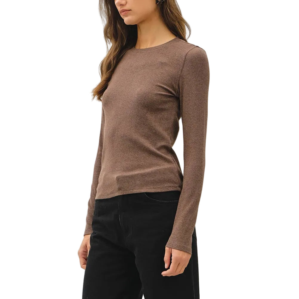 A woman modeling a fitted long-sleeve crewneck sweater in taupe brown, paired with black cropped pants and black ankle boots, against a plain off-white studio background.