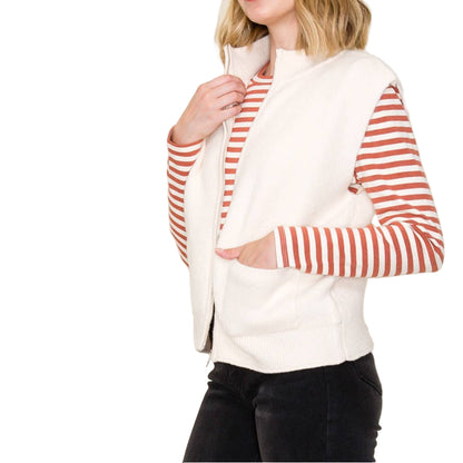 Woman wearing a white vest with red striped sleeves against a plain background