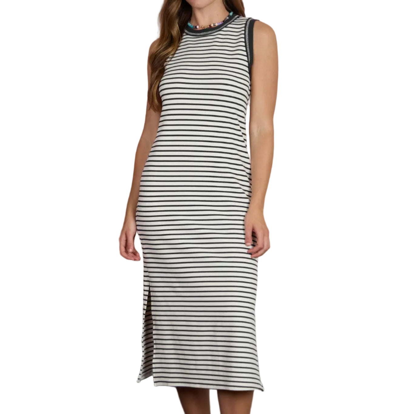 Woman wearing a striped dress standing in front of a blurred background with a table and decorative items.