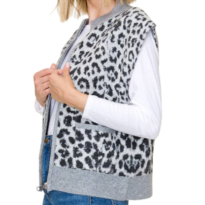 Woman wearing a leopard print vest over a white shirt with blue jeans on a beige background