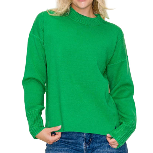 Person wearing a green sweater and blue jeans against a plain background
