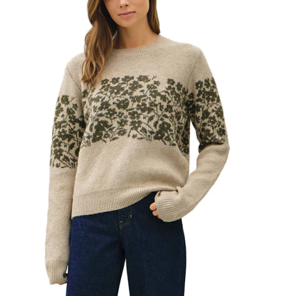 Woman wearing a patterned sweater and blue jeans against a white background