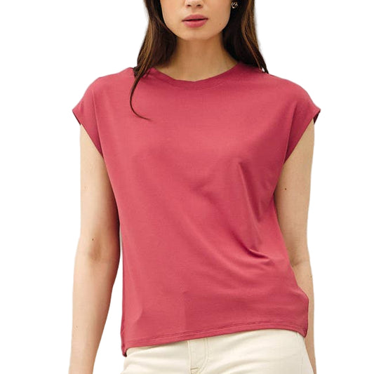 Woman wearing a pink t-shirt and white pants against a white background