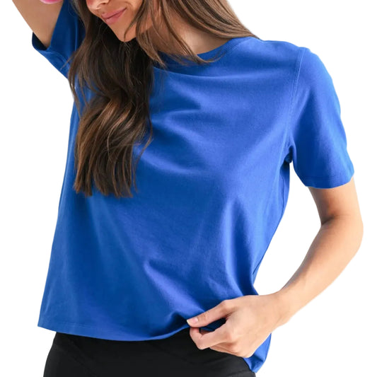 Woman wearing a blue shirt, black leggings, and a pink cap on a white background
