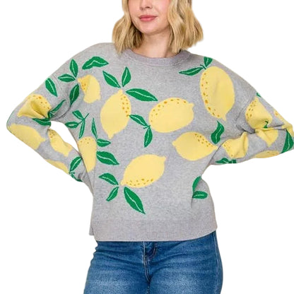Woman wearing a gray sweater with lemon designs and blue jeans on a beige background