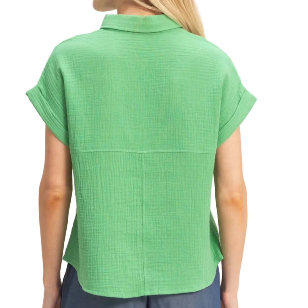 Woman wearing a green short-sleeve top and blue shorts on a beige background