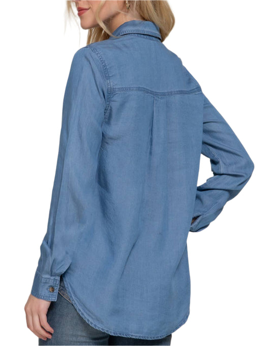 Woman wearing a blue denim shirt against a plain background