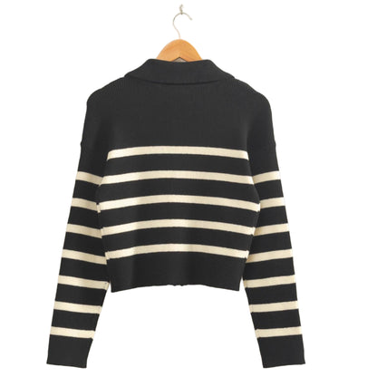Black and white striped sweater on a hanger against a beige wall