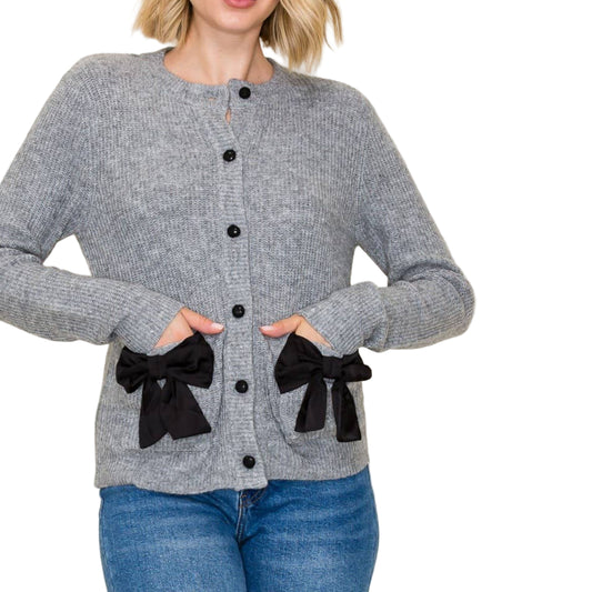 Woman wearing a gray cardigan with black bows on a white background