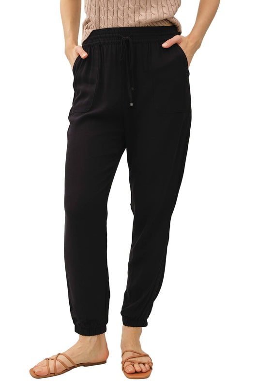 Person wearing black jogger pants with a neutral background