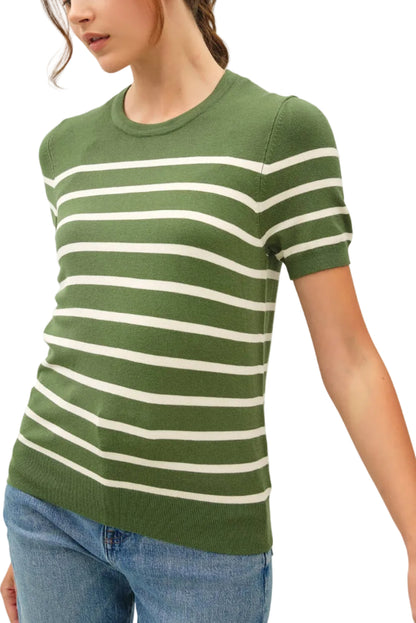 Woman wearing a green and white striped shirt with blue jeans on a plain background