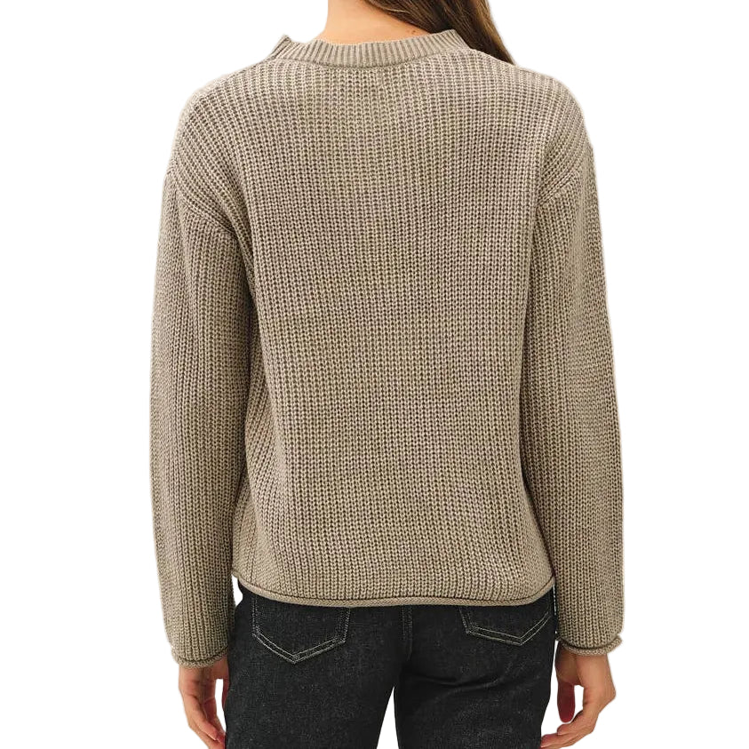 A woman viewed from the back wearing a beige ribbed knit sweater, dark blue flared jeans, and black sneakers against a plain white studio background.
