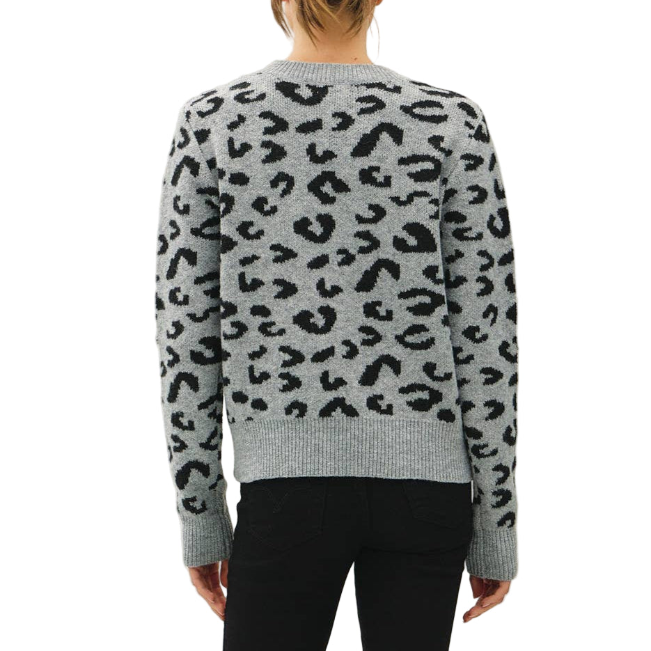 Person wearing a gray sweater with black leopard print pattern and black pants on a white background