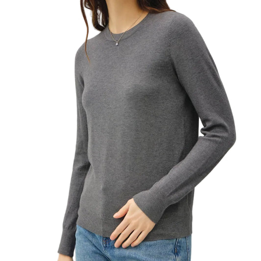 Woman wearing a gray sweater and blue jeans against a plain background