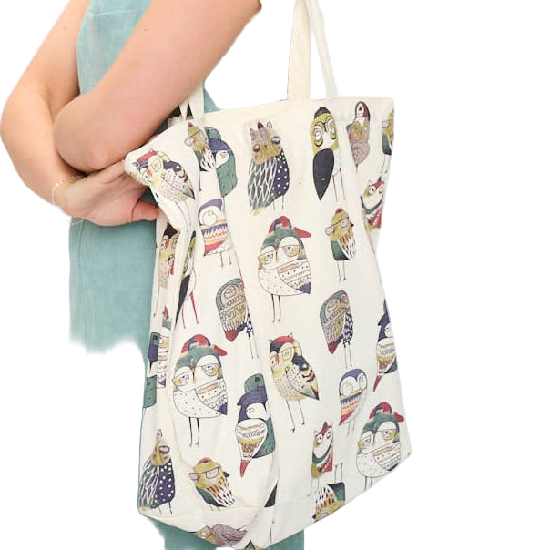 Woman holding a tote bag with a cat pattern against a white background