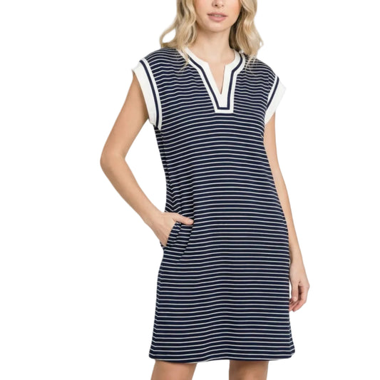Woman wearing a navy and white striped dress on a light pink background