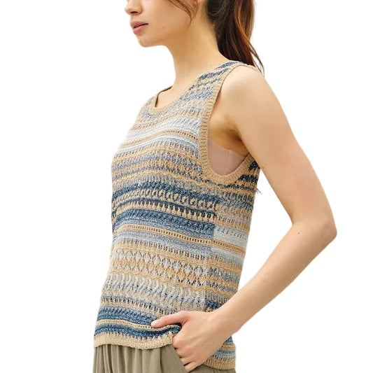 Woman wearing a sleeveless patterned top and wide-leg pants against a white background