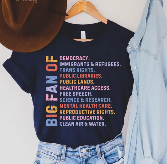 Navy blue t-shirt with colorful text on a hanger with jeans and a hat.