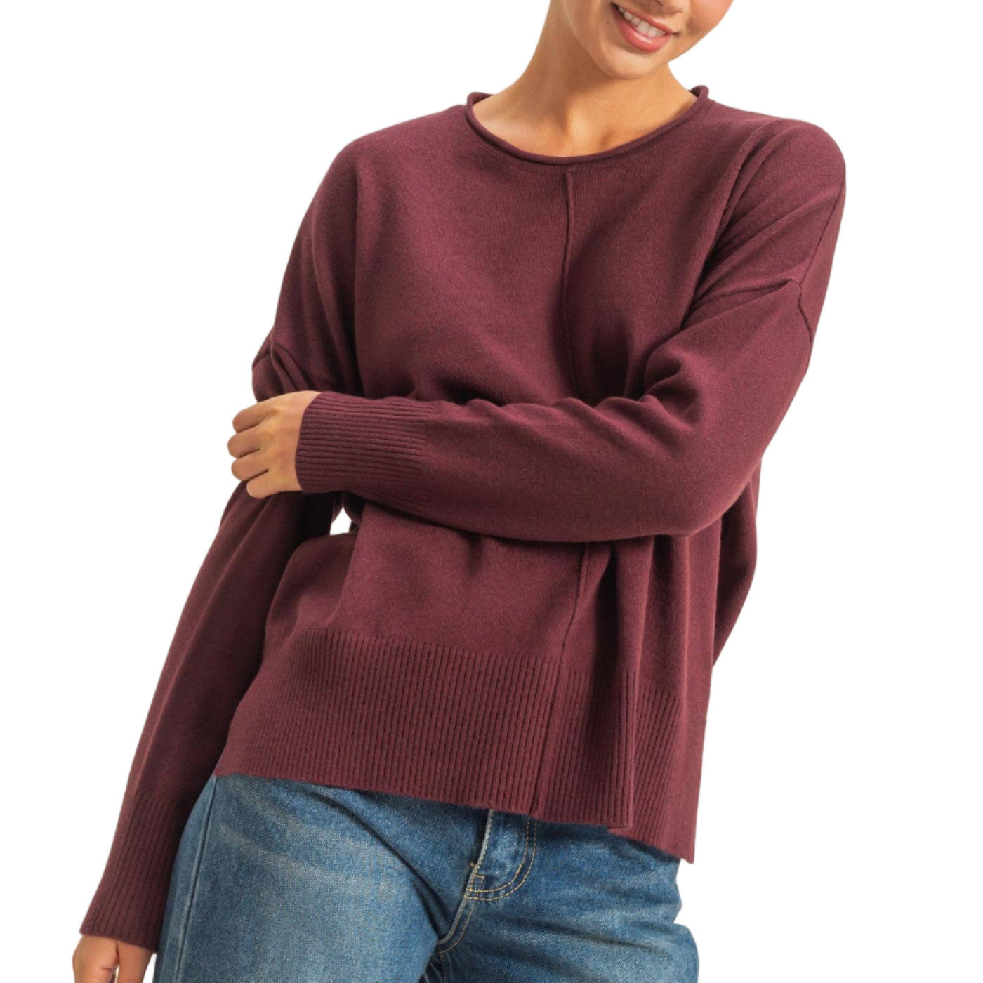 Person wearing a burgundy sweater and blue jeans on a plain background