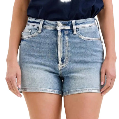 Denim shorts worn by a person on a plain background