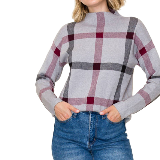 Woman wearing a plaid sweater and jeans against a plain background