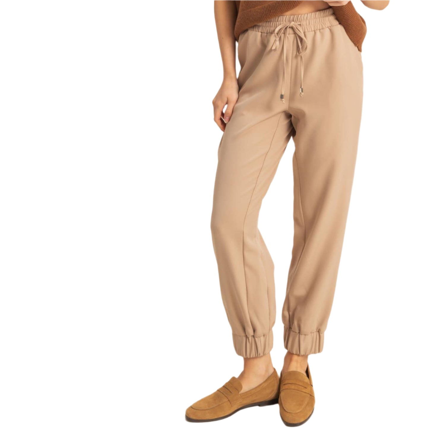 Woman wearing a brown top and beige pants against a white background
