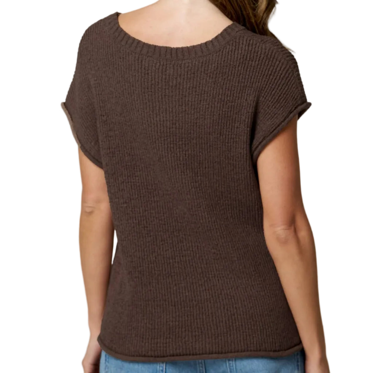 Woman wearing a brown knitted top and blue jeans on a plain background